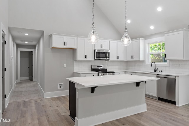 kitchen featuring white cabinets, lofted ceiling, sink, appliances with stainless steel finishes, and a center island