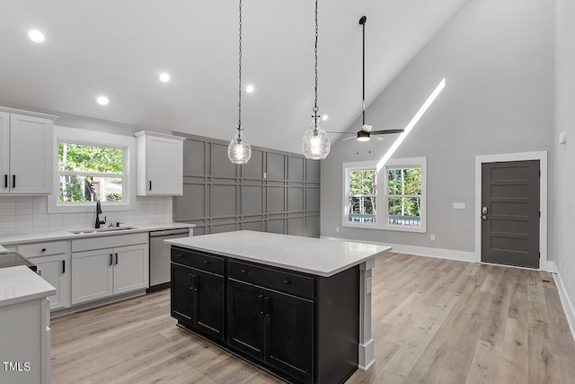 kitchen with a healthy amount of sunlight, stainless steel dishwasher, a kitchen island, and sink