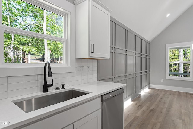 kitchen featuring dishwasher, vaulted ceiling, white cabinetry, and a wealth of natural light