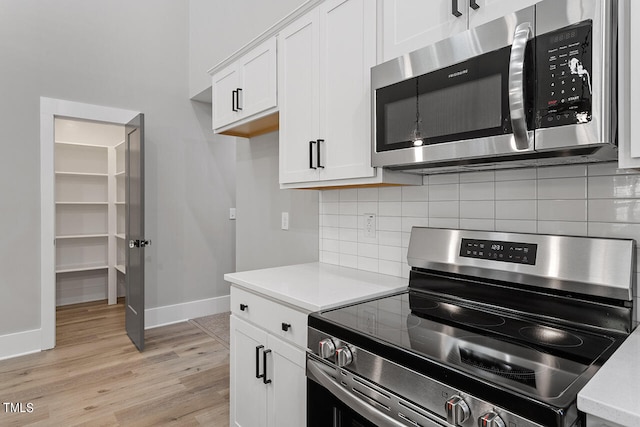 kitchen featuring white cabinets, stainless steel appliances, backsplash, and light hardwood / wood-style flooring