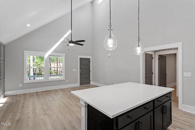 kitchen featuring ceiling fan, light wood-type flooring, high vaulted ceiling, and a center island