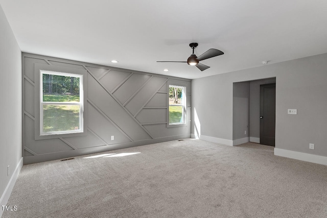 empty room with ceiling fan, light colored carpet, and a healthy amount of sunlight