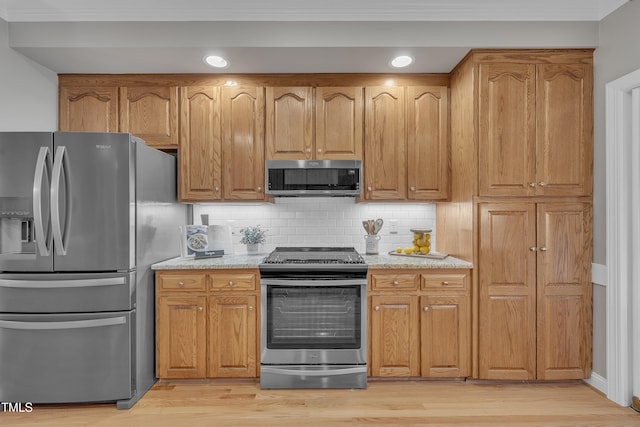 kitchen featuring backsplash, light stone countertops, stainless steel appliances, and light wood-type flooring