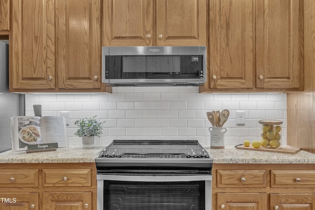 kitchen featuring decorative backsplash, stainless steel appliances, and light stone countertops