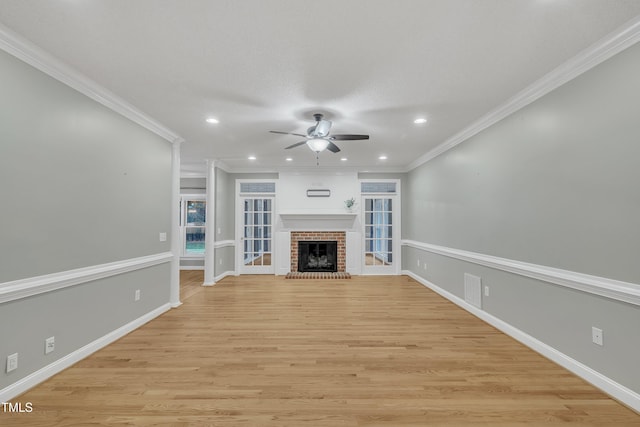 unfurnished living room featuring a brick fireplace, ceiling fan, light wood-type flooring, and ornamental molding