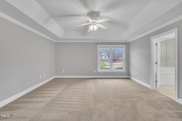 carpeted empty room featuring ceiling fan, a raised ceiling, ornamental molding, and a textured ceiling