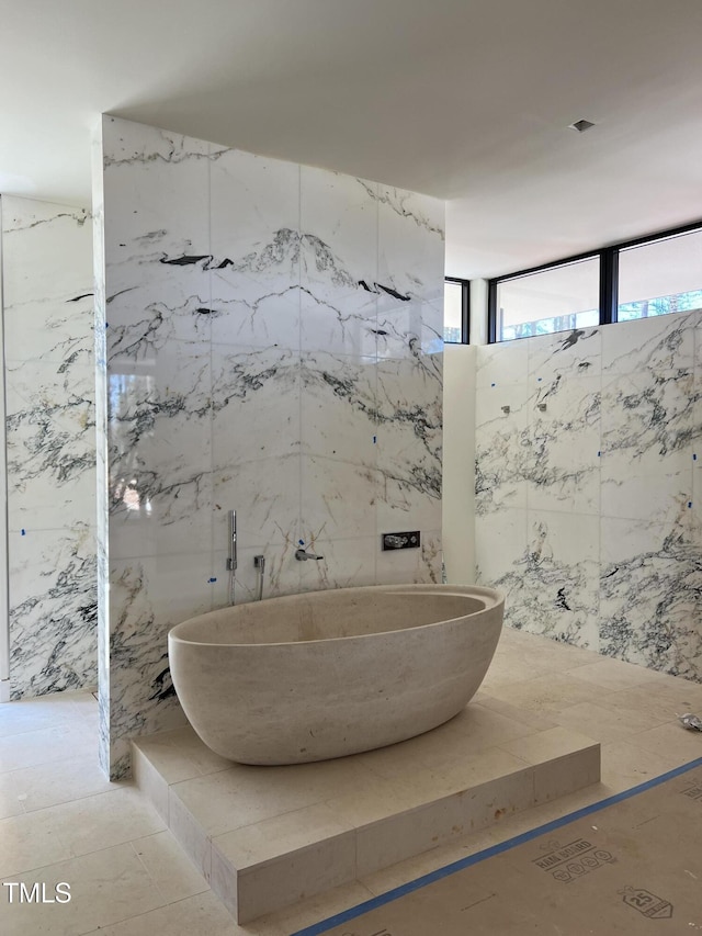 full bathroom with stone wall and a freestanding tub