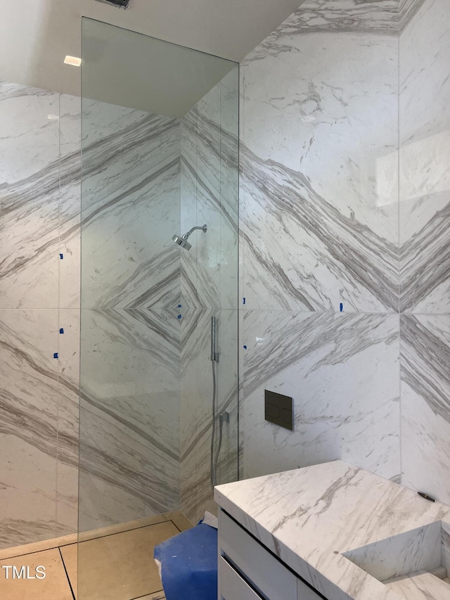 full bathroom featuring a marble finish shower and vanity