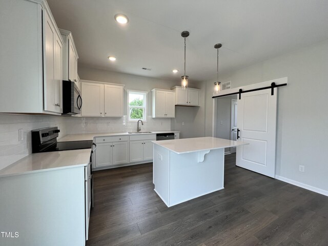 kitchen featuring a barn door, dark hardwood / wood-style floors, white cabinets, sink, and backsplash