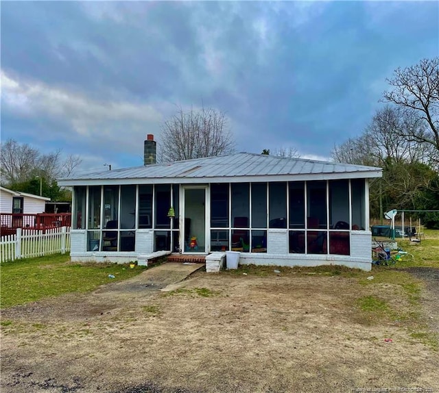 rear view of house featuring a yard and a sunroom