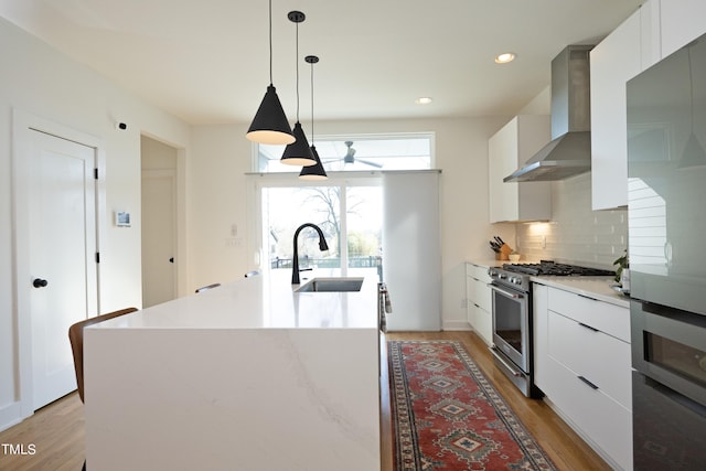 kitchen featuring light hardwood / wood-style flooring, hanging light fixtures, high end range, and wall chimney exhaust hood