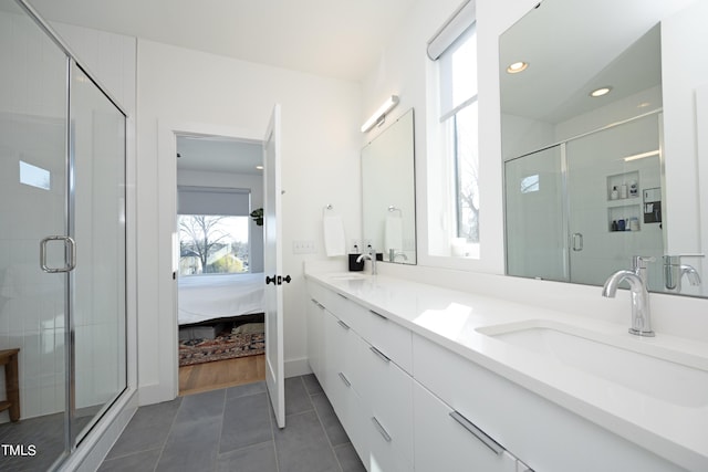 bathroom with a shower with door, double sink, vanity with extensive cabinet space, and tile flooring