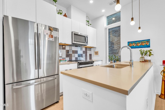 kitchen featuring visible vents, a sink, tasteful backsplash, stainless steel appliances, and white cabinets