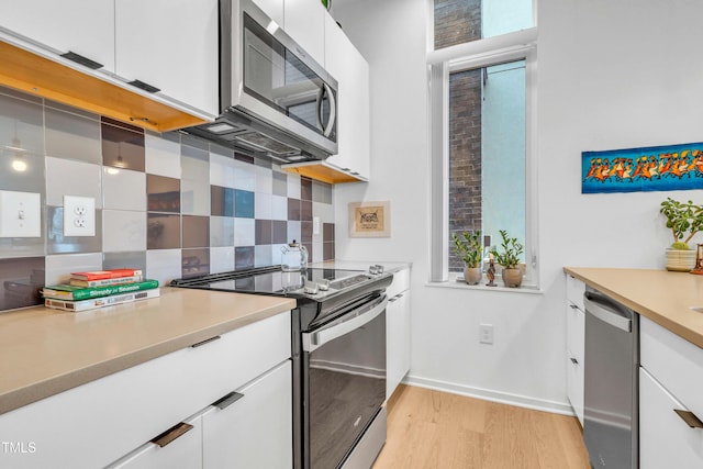 kitchen featuring white cabinetry, light wood-style floors, tasteful backsplash, and appliances with stainless steel finishes