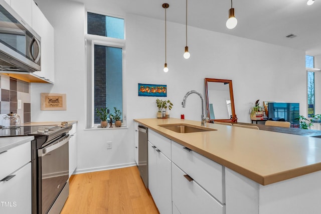 kitchen with visible vents, white cabinets, stainless steel appliances, and a sink