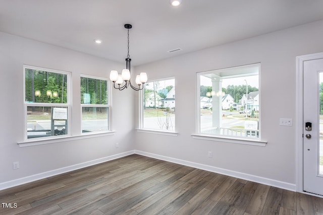 unfurnished dining area with dark hardwood / wood-style flooring and a chandelier