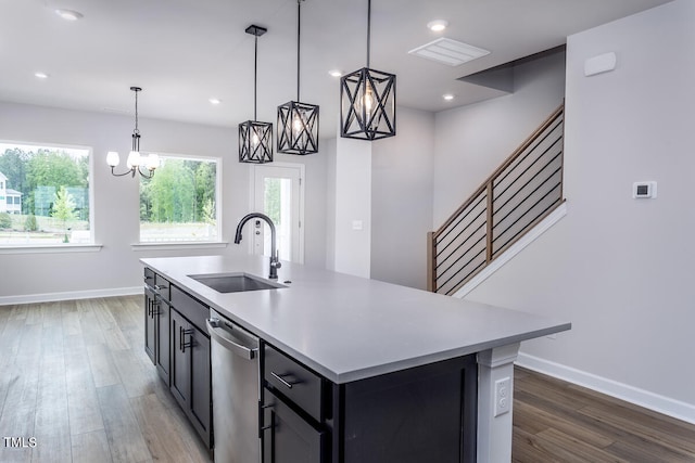 kitchen featuring wood-type flooring, hanging light fixtures, sink, and an island with sink