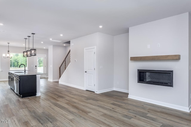 kitchen featuring decorative light fixtures, hardwood / wood-style flooring, an island with sink, sink, and a notable chandelier