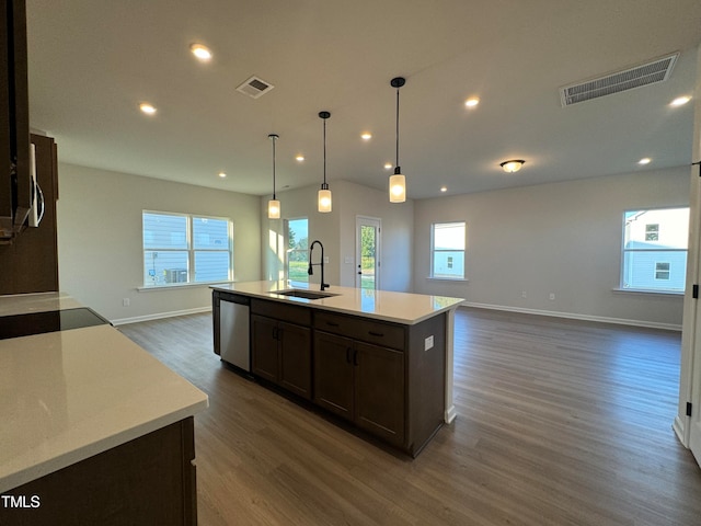 kitchen featuring dark hardwood / wood-style flooring, a kitchen island with sink, sink, pendant lighting, and dishwasher