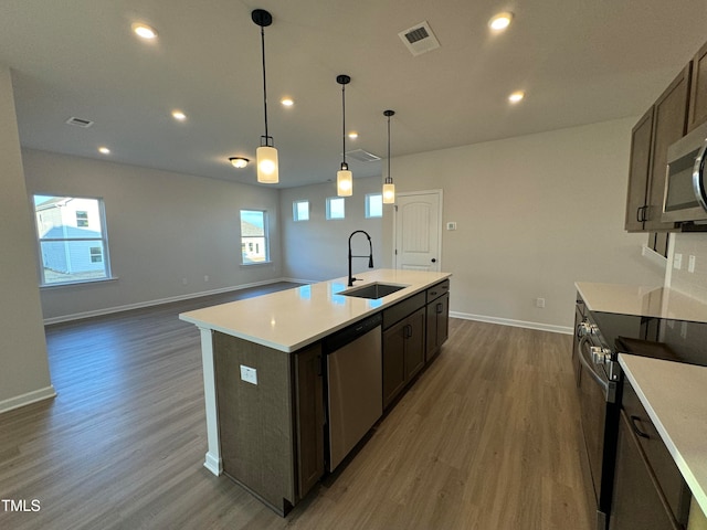 kitchen featuring a wealth of natural light, sink, an island with sink, and appliances with stainless steel finishes