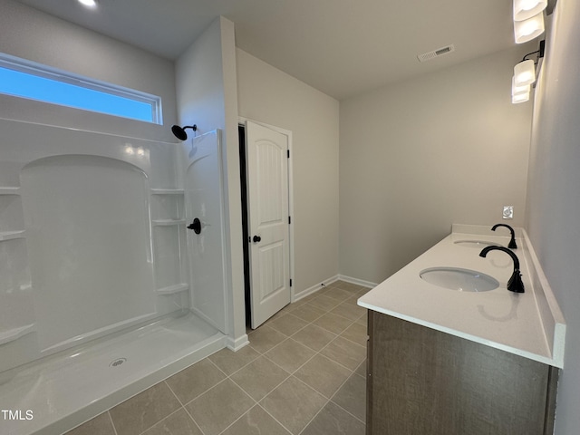 bathroom with tile patterned flooring, vanity, and walk in shower