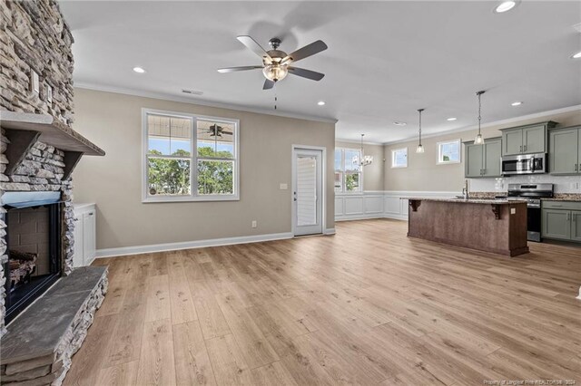 unfurnished living room featuring a stone fireplace, light wood-type flooring, and a wealth of natural light