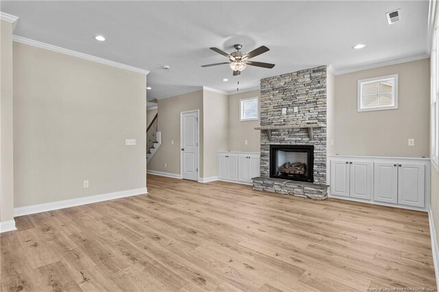 unfurnished living room featuring a fireplace, crown molding, light wood-type flooring, and ceiling fan