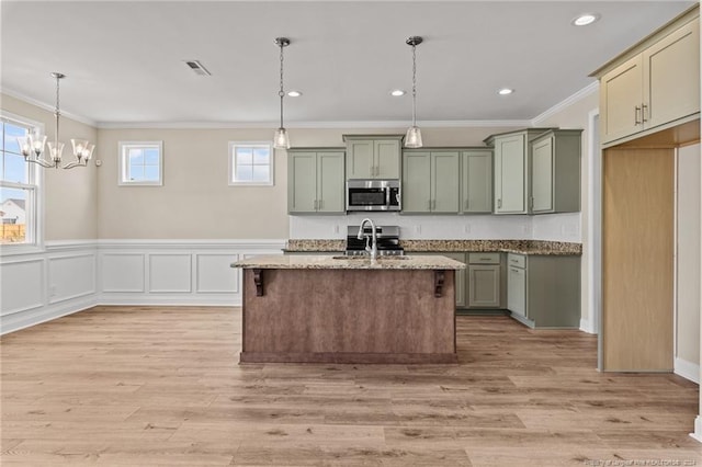 kitchen featuring stainless steel appliances, hanging light fixtures, a wealth of natural light, and light wood-type flooring