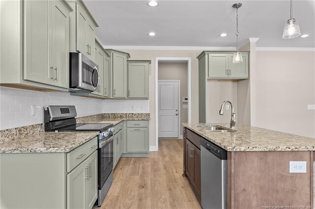 kitchen featuring appliances with stainless steel finishes, sink, hanging light fixtures, light wood-type flooring, and ornamental molding