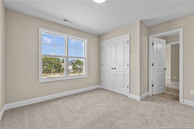 unfurnished bedroom featuring a closet and light colored carpet