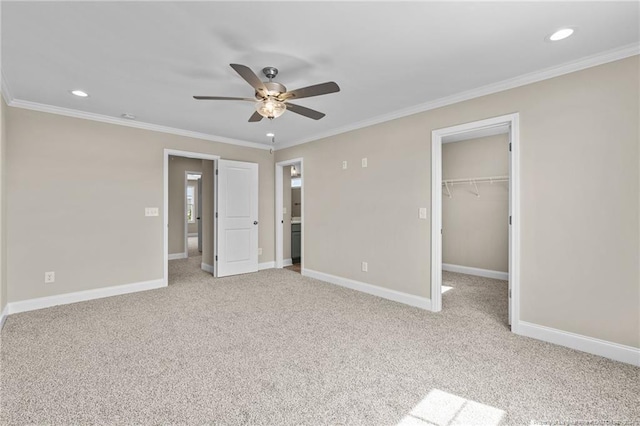 unfurnished bedroom with crown molding, a spacious closet, light colored carpet, and ceiling fan