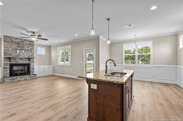 kitchen featuring light hardwood / wood-style flooring, ceiling fan with notable chandelier, pendant lighting, dark brown cabinetry, and sink