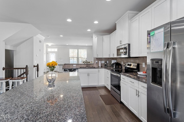 1001 Drayman Pl, Apex, NC 27502 - kitchen with appliances with stainless steel finishes, dark stone countertops, white cabinetry, a sink, and recessed lighting