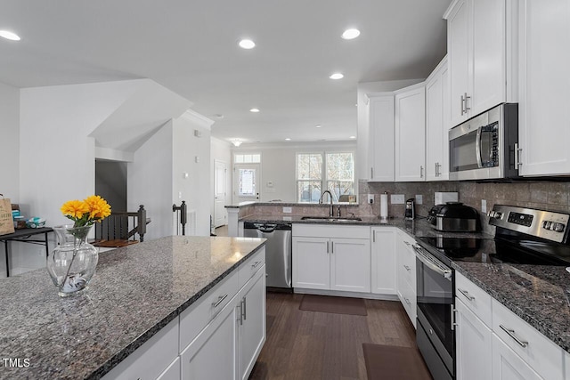 1001 Drayman Pl, Apex, NC 27502 - kitchen featuring stainless steel appliances, a sink, dark wood-style floors, white cabinetry, and dark stone countertops