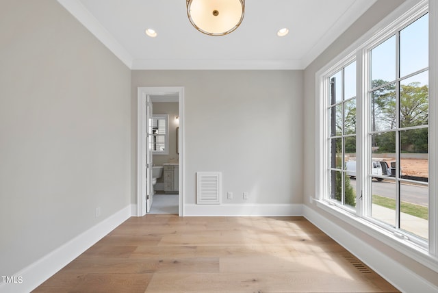 empty room with crown molding and light hardwood / wood-style flooring