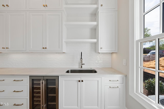 bar featuring wine cooler, sink, tasteful backsplash, and white cabinets