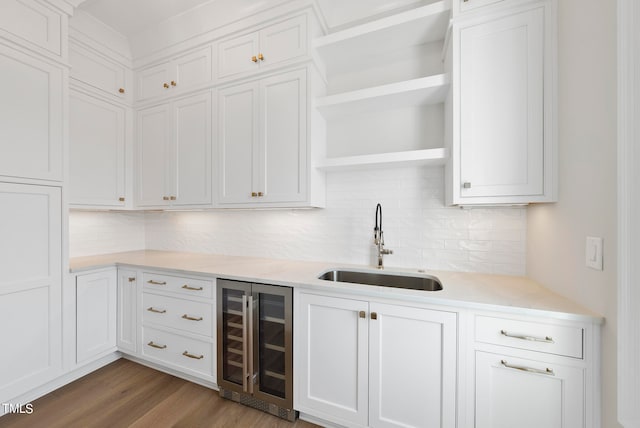 kitchen with beverage cooler, hardwood / wood-style floors, backsplash, and sink