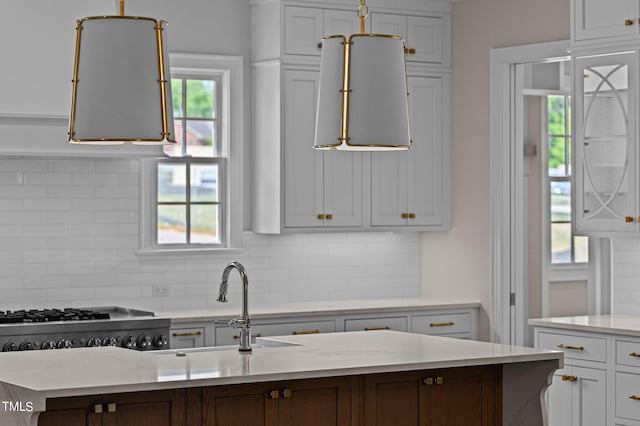 kitchen featuring backsplash, plenty of natural light, white cabinets, and light stone countertops