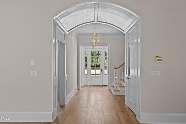 entrance foyer with ornamental molding, lofted ceiling, and light wood-type flooring