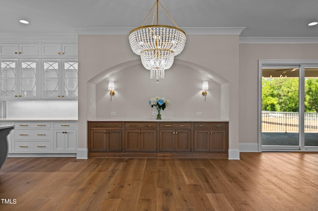 interior space featuring hardwood / wood-style floors, a chandelier, tasteful backsplash, and crown molding