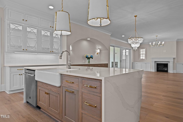 kitchen with stainless steel dishwasher, light hardwood / wood-style floors, tasteful backsplash, and a kitchen island with sink