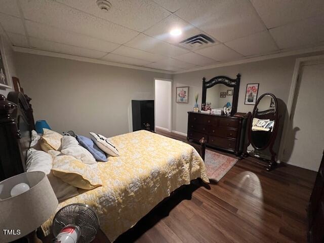 bedroom with crown molding, dark hardwood / wood-style flooring, and a drop ceiling