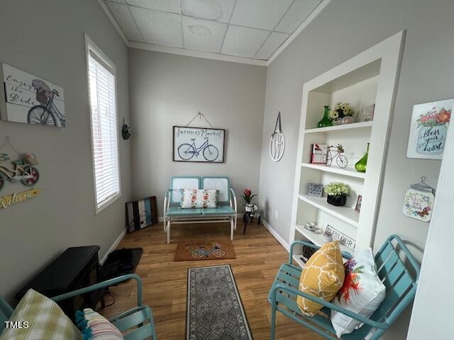 sitting room with hardwood / wood-style floors, a paneled ceiling, and built in features