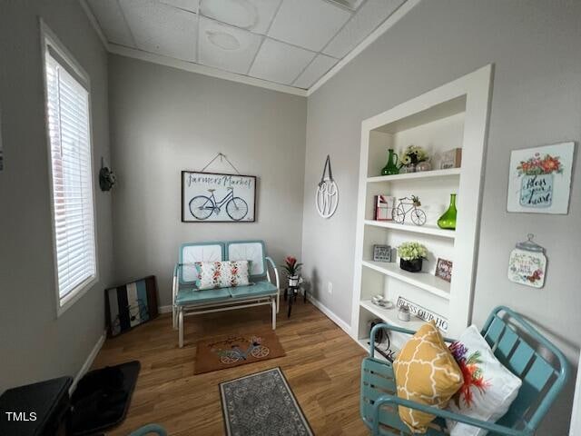 sitting room featuring a paneled ceiling, hardwood / wood-style flooring, and built in features