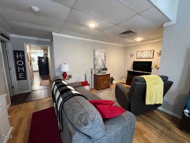 living room with hardwood / wood-style floors, a drop ceiling, and crown molding