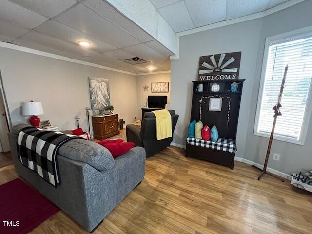 living room featuring hardwood / wood-style floors, a drop ceiling, and ornamental molding