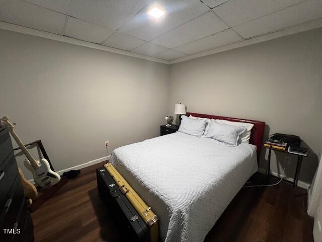 bedroom featuring a drop ceiling and dark hardwood / wood-style flooring