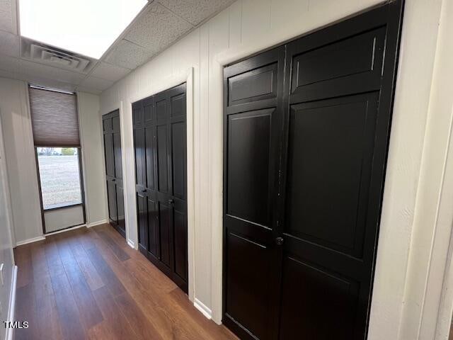 hallway featuring a drop ceiling and dark hardwood / wood-style flooring