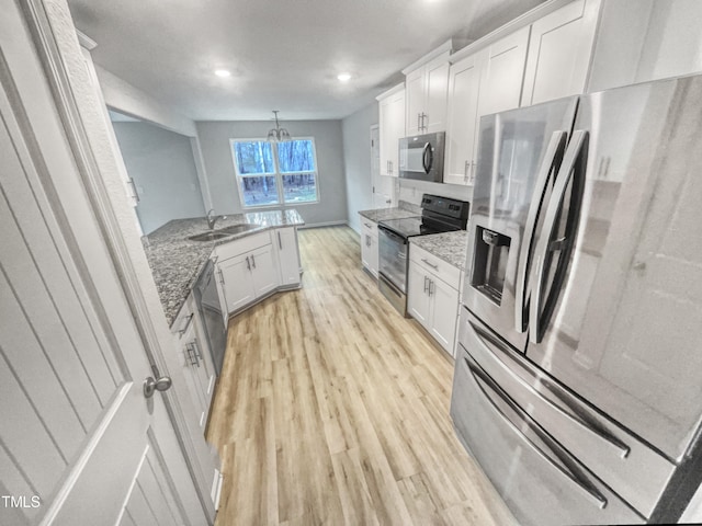 kitchen with sink, white cabinetry, stainless steel appliances, light stone countertops, and light hardwood / wood-style floors