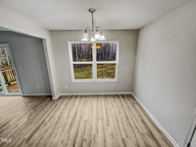 unfurnished dining area featuring light hardwood / wood-style flooring, a chandelier, and a wealth of natural light